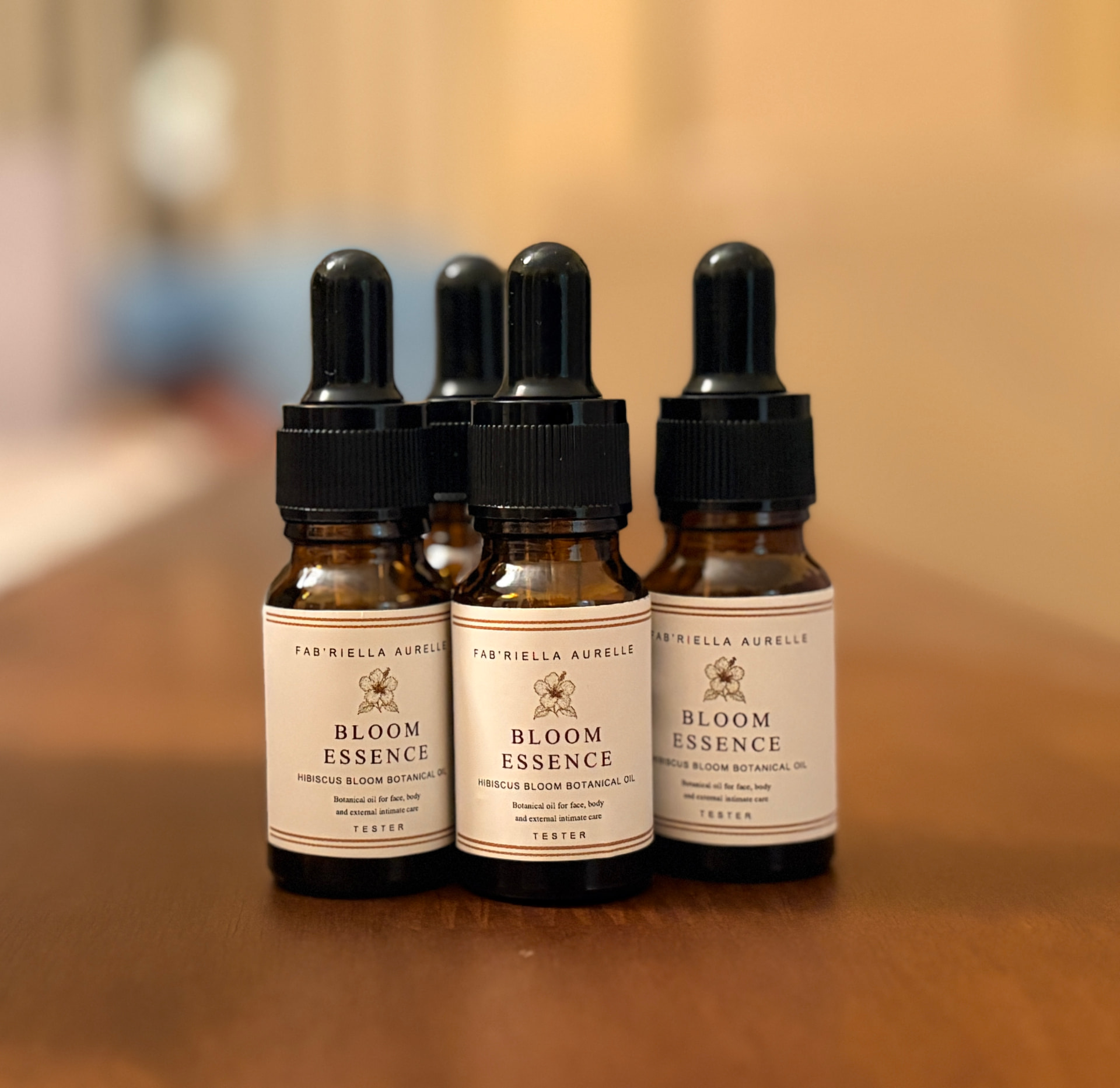 Hand-labelled Bloom Essence Hibiscus Bloom Botanical Oil bottles on a warm wooden surface